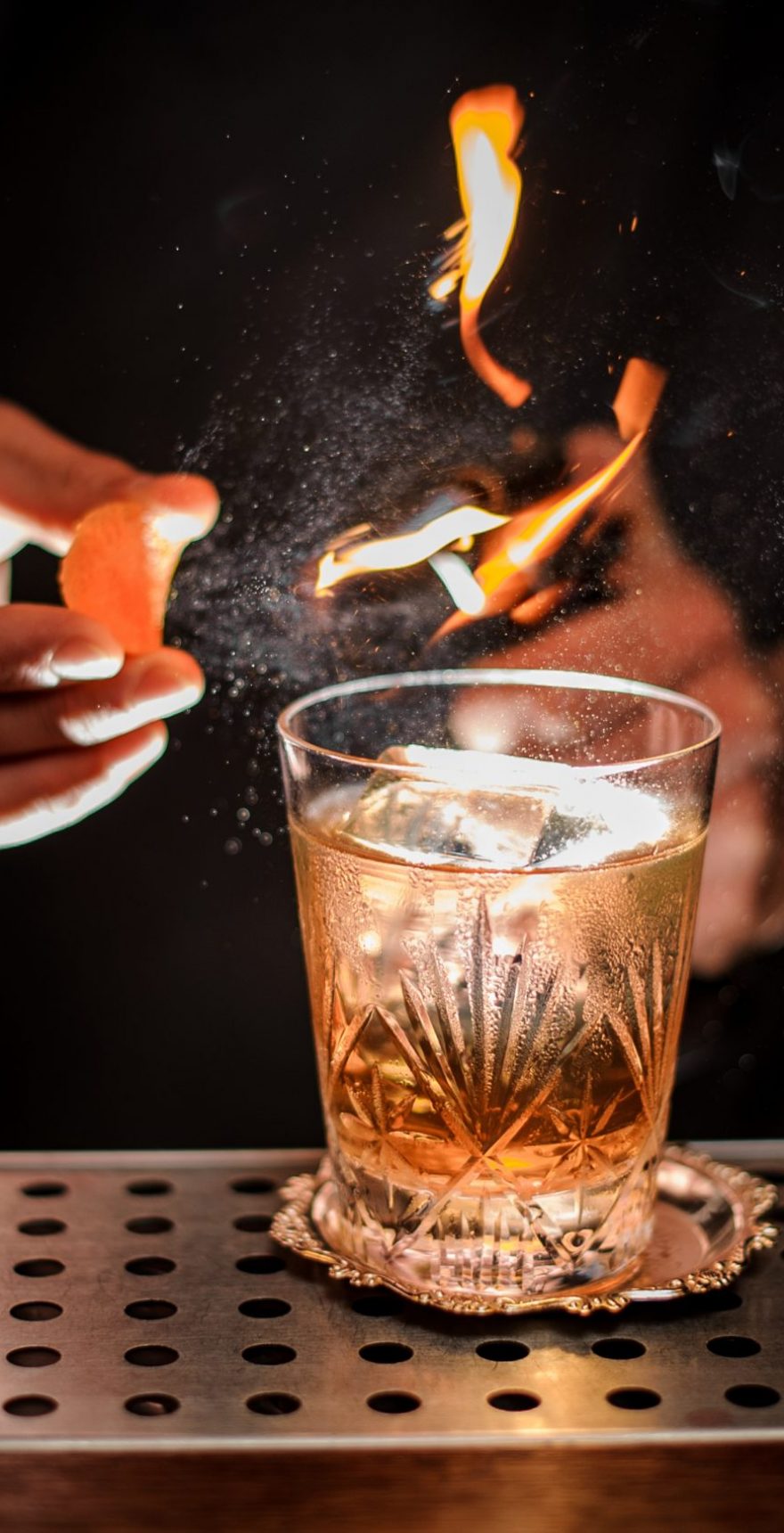 Barman making a fresh and tasty old fashioned cocktail with orange peel and smoke note on the bar counter